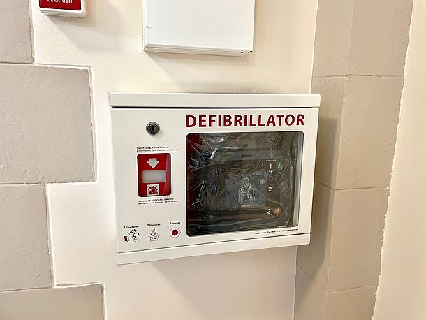 Defibrillator im Eingangsbereich im Erdgeschoss, das Gerät wird von den Mitarbeitenden gebracht, keine Aushändigung an 3.!
